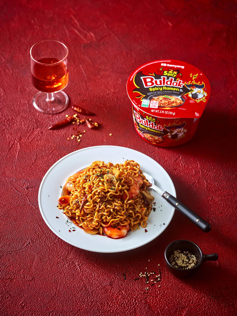Spicy noodles with a glass of red drink on a red background